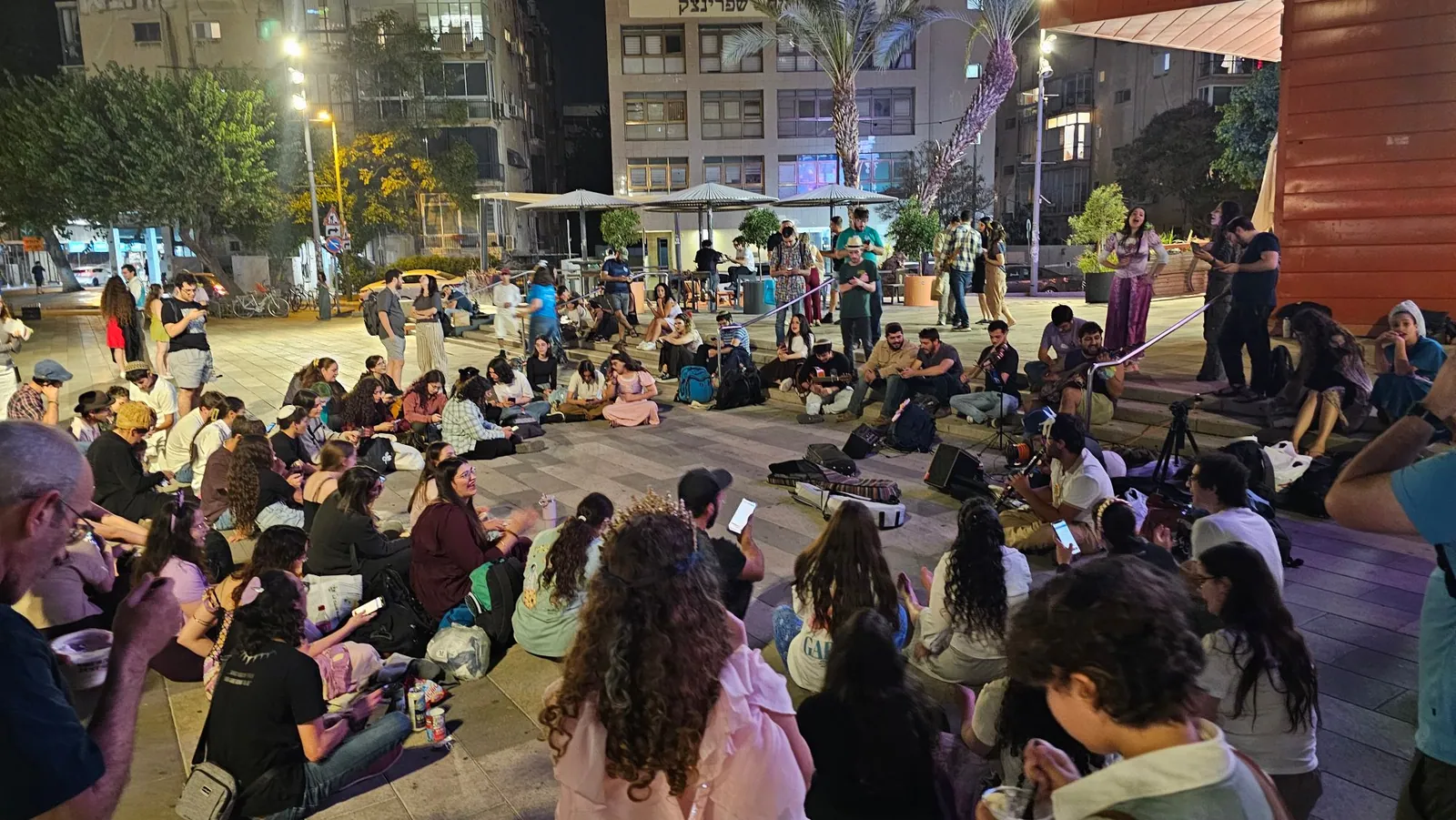 המעגלון אחרי ההקרנה: כולם יושבים במעגל על הרחבה של הסינמטק, עם גיטרות, כינור וקלרינט